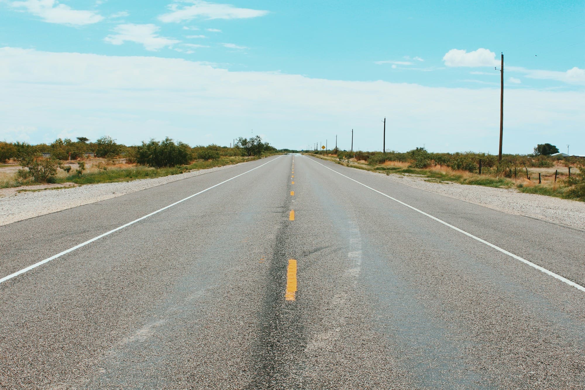 A straight, empty road under a bright sky