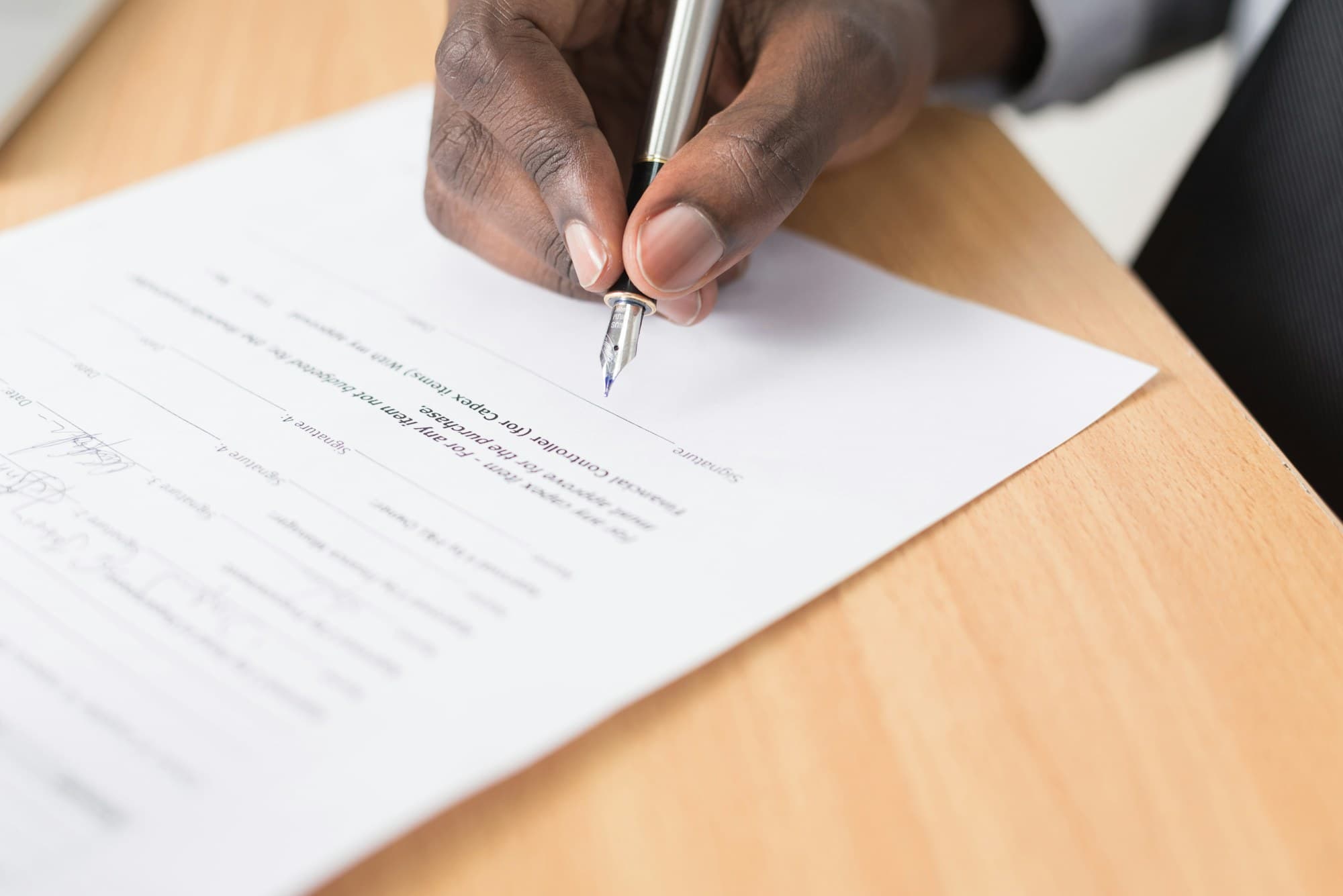 A hand signing a document at a desk