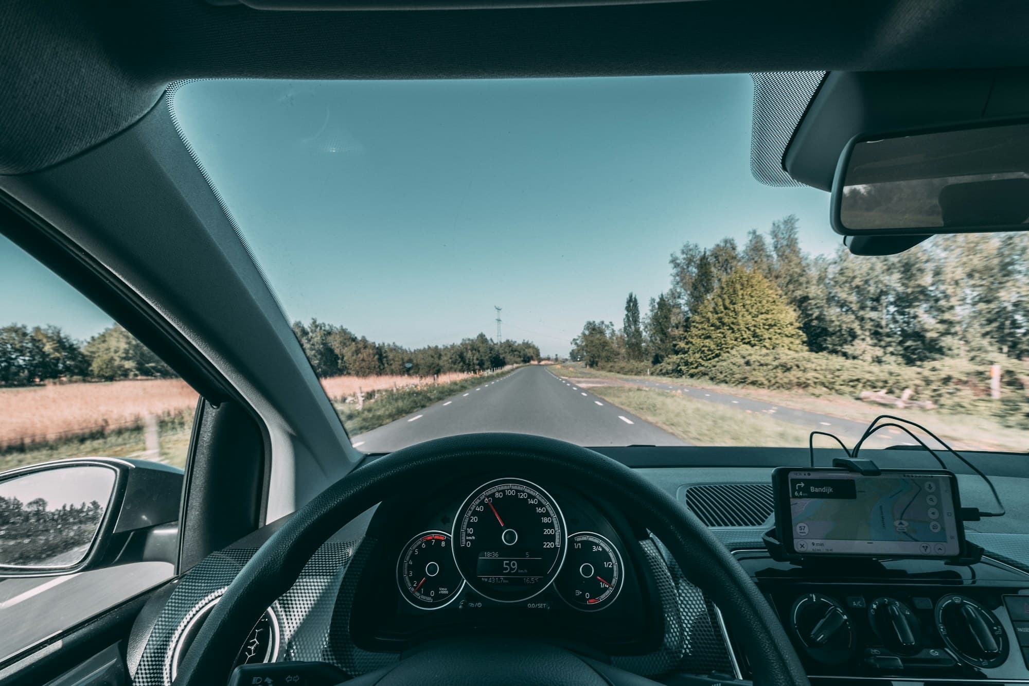 View over a steering wheel onto an open road in daylight