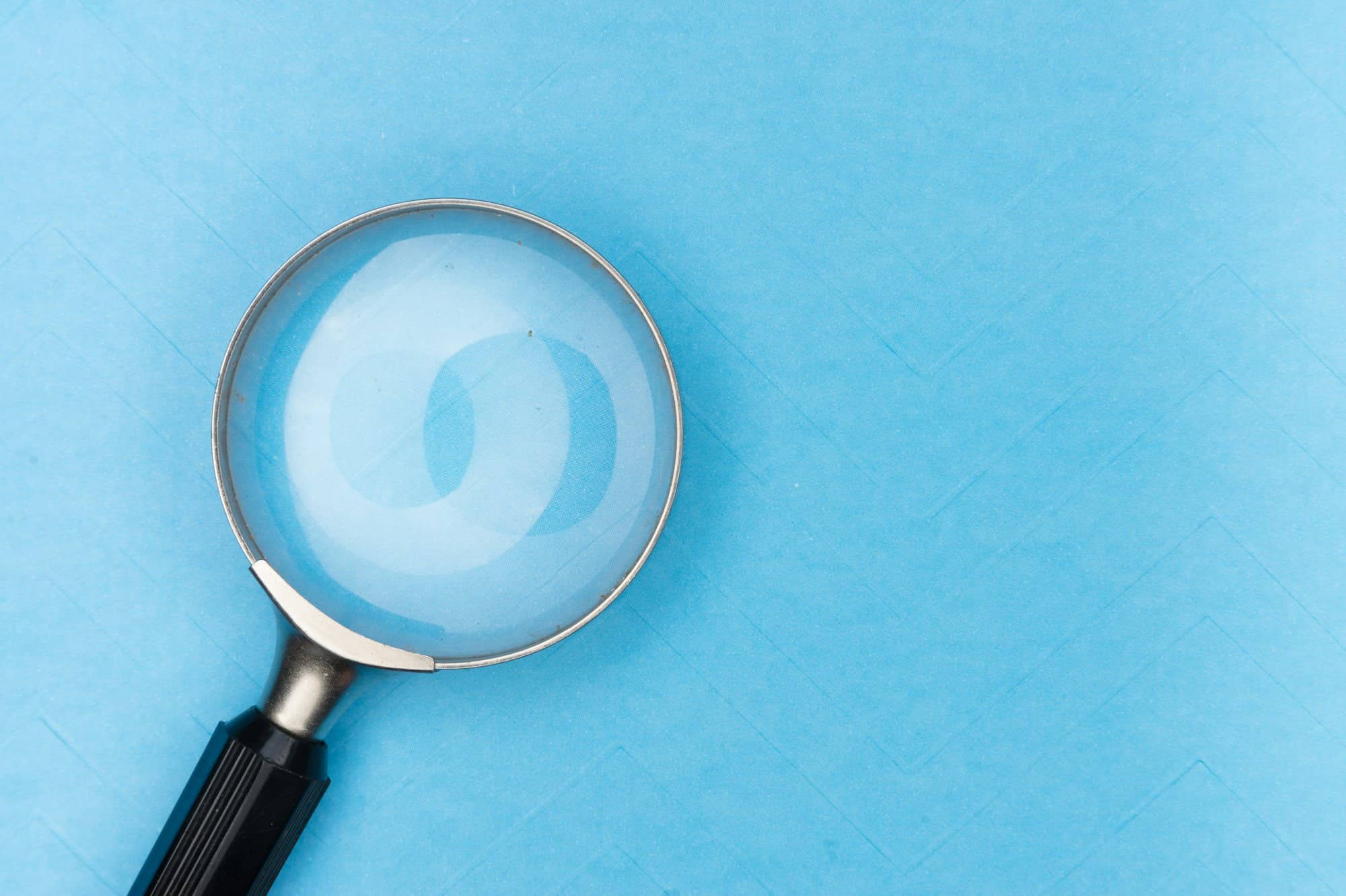A magnifying glass on a pale blue surface
